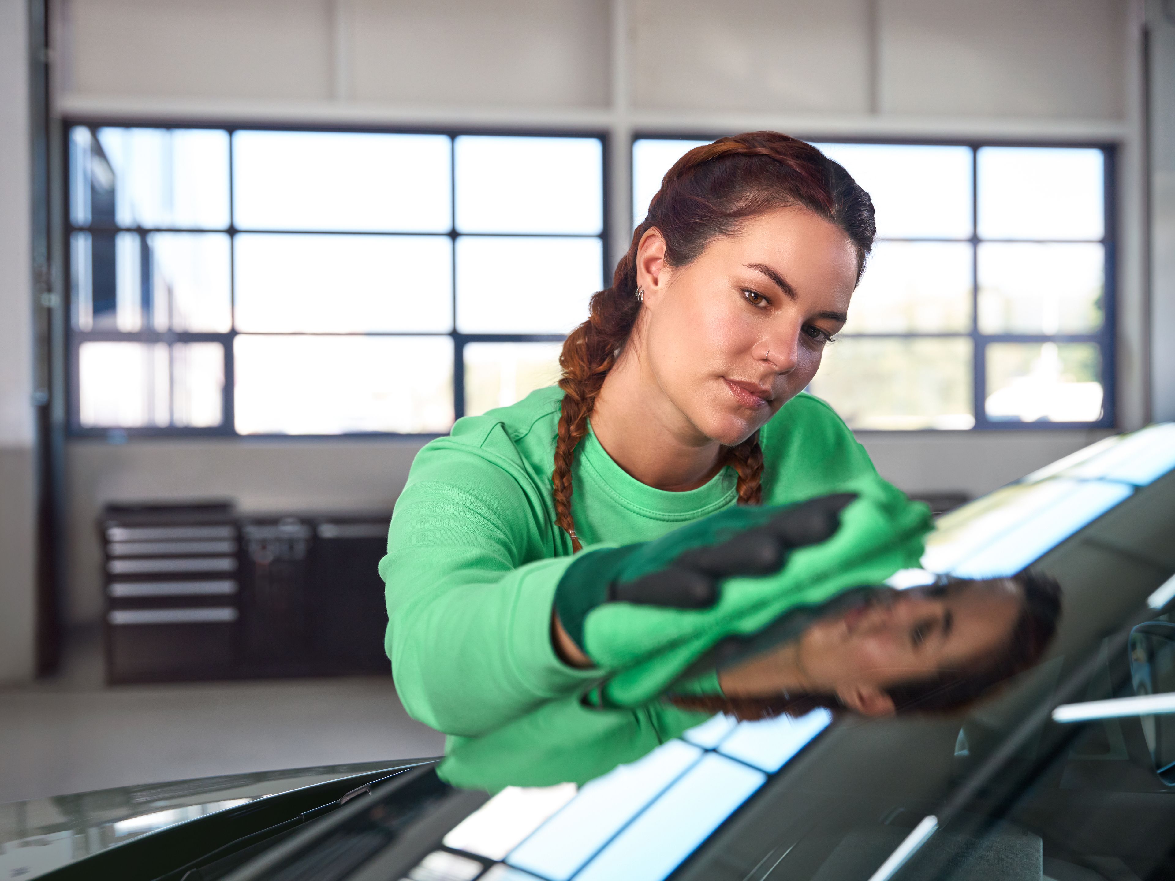 Serviserka preverja poškodbo vetrobranskega stekla na vozilu Škoda v servisni delavnici