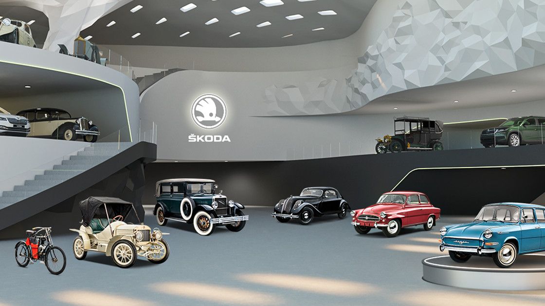 Razstavni prostor s starinskimi avtomobili znamke Škoda v sodobno oblikovani galeriji. Različni modeli so postavljeni na izstopajočih mestih, nekateri na dvignjenih platformah. Ozadje je moderno in futuristično, z logotipom Škoda na steni.