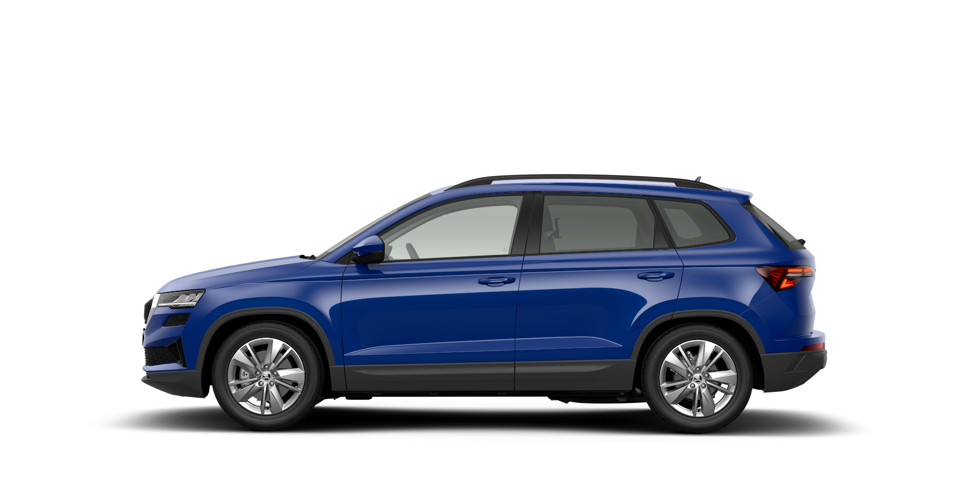 Stranski pogled na moder SUV Škoda Karoq, parkiran na beli podlagi. Vozilo ima štiri vrata in srebrna platišča. Okna so rahlo zatemnjena.