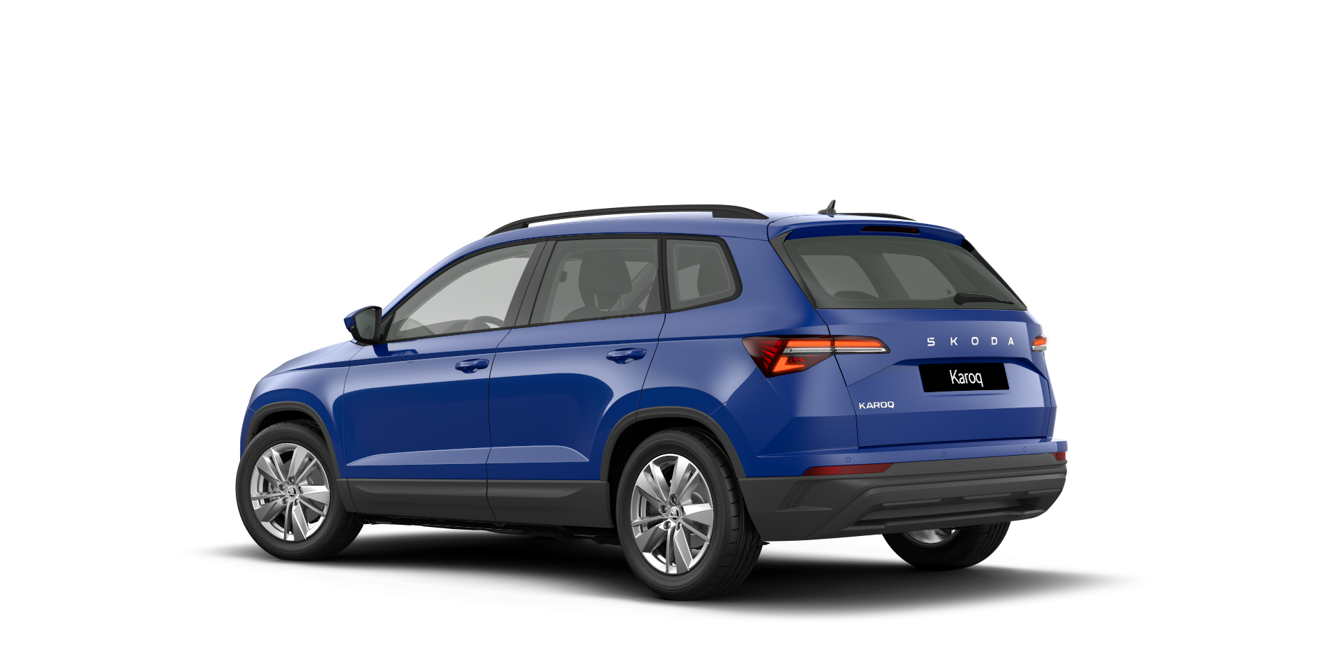 Modri Škoda Karoq, parkiran na beli podlagi. Avto je po dizajnu SUV, s štirimi vrati in zadnjim prtljažnikom. Ima srebrne platišča in je namenjen družinski uporabi.