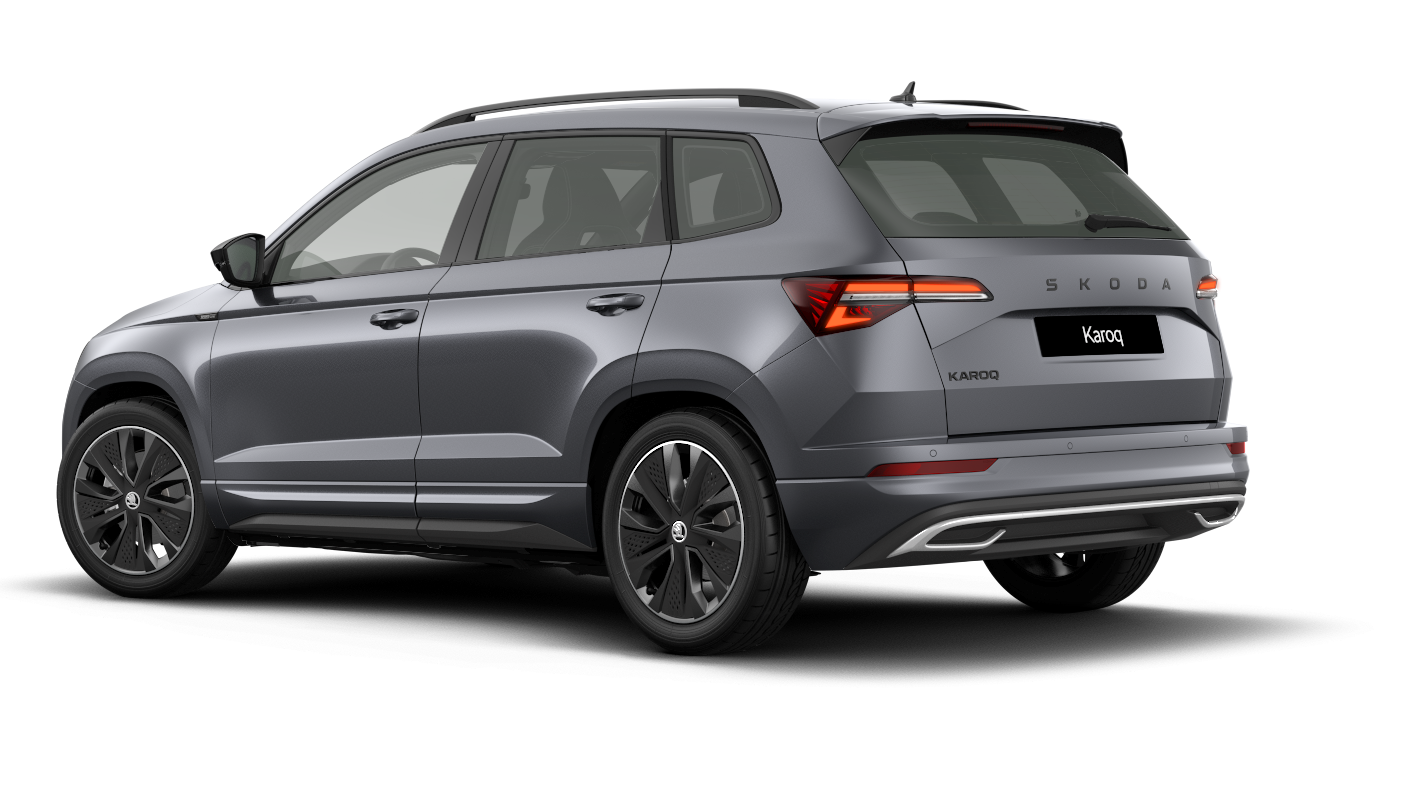 Sivo osebno vozilo Škoda Karoq je parkirano v levem profilu, z elegantno oblikovanimi linijami in sodobnimi žarometi. Avto ima velike pnevmatike in aerodinamično oblikovan zadek.