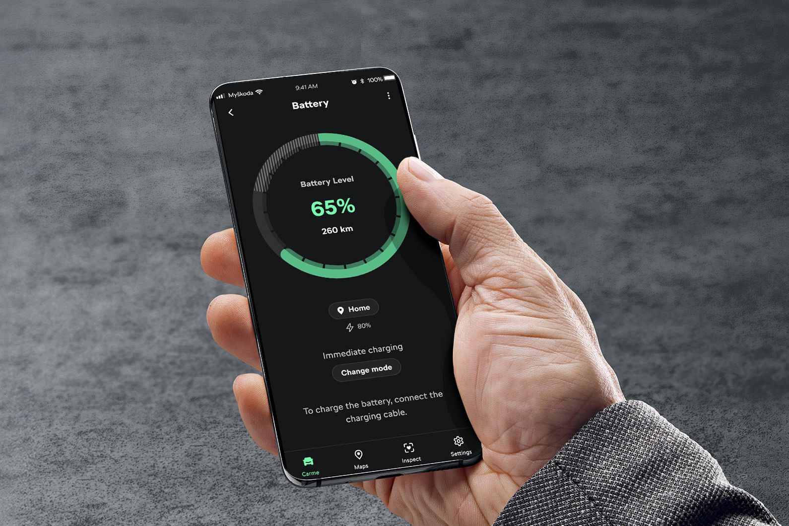 Stranka v roki drži mobitel na katerem je viden ekran s podatki o stopnji polnjena visokonapetostne baterije v vozilu Škoda