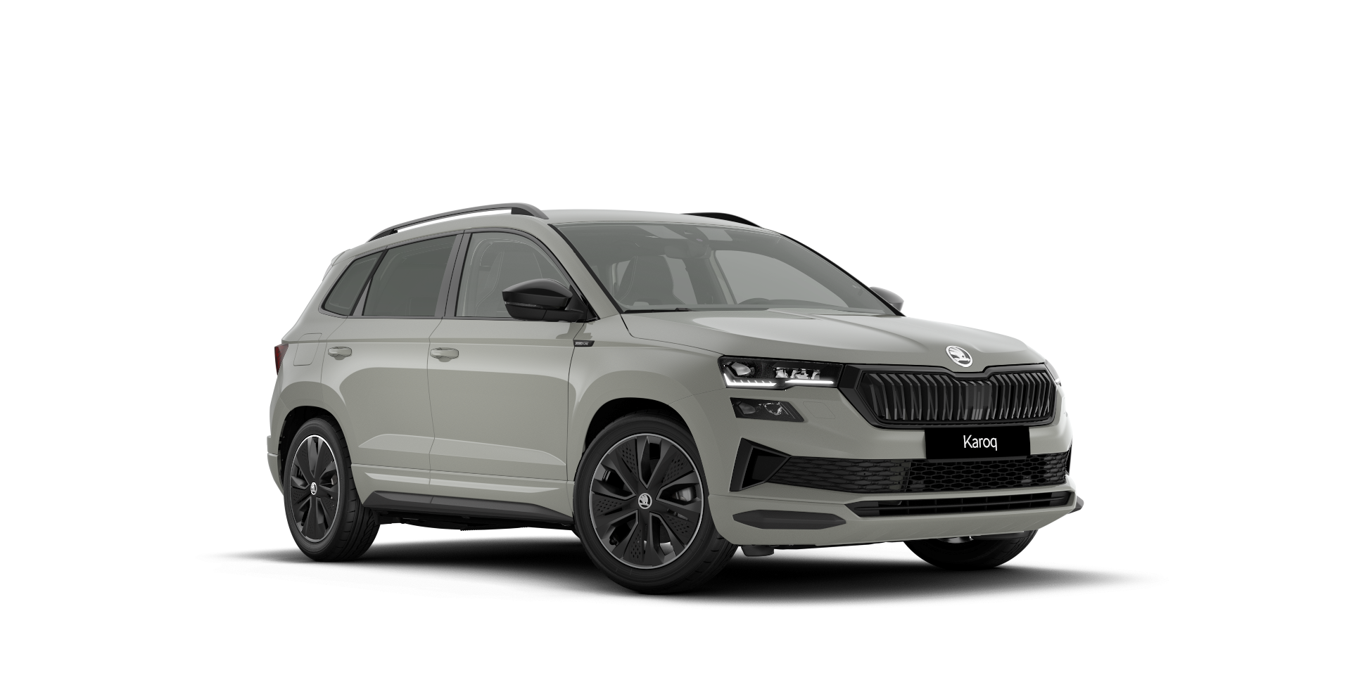Slika prikazuje srebrno siv SUV vozilo znamke Škoda Karoq. Avto ima črne platišča, sprednje LED žaromete in modern oblikovan sprednji del. Karoserija vozila je kompaktna in elegantna.