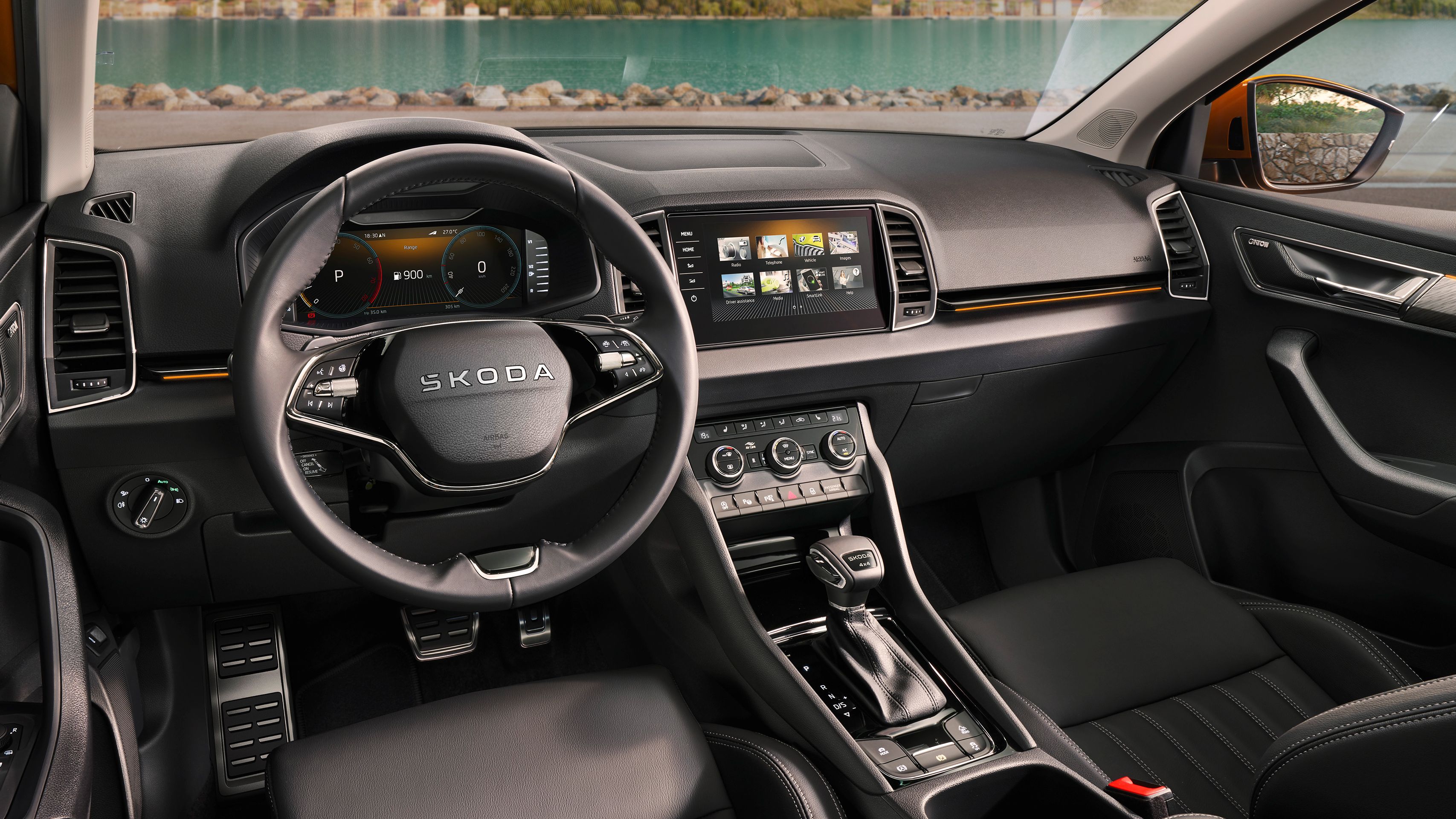 Notranjost Škoda Karoq z vidnim volanom, osrednjo konzolo in velikim zaslonom na dotik. Osebni in moderni dizajn z usnjenimi sedeži. Na voljo so različne kontrole za klimatsko napravo in multimedijske funkcije.