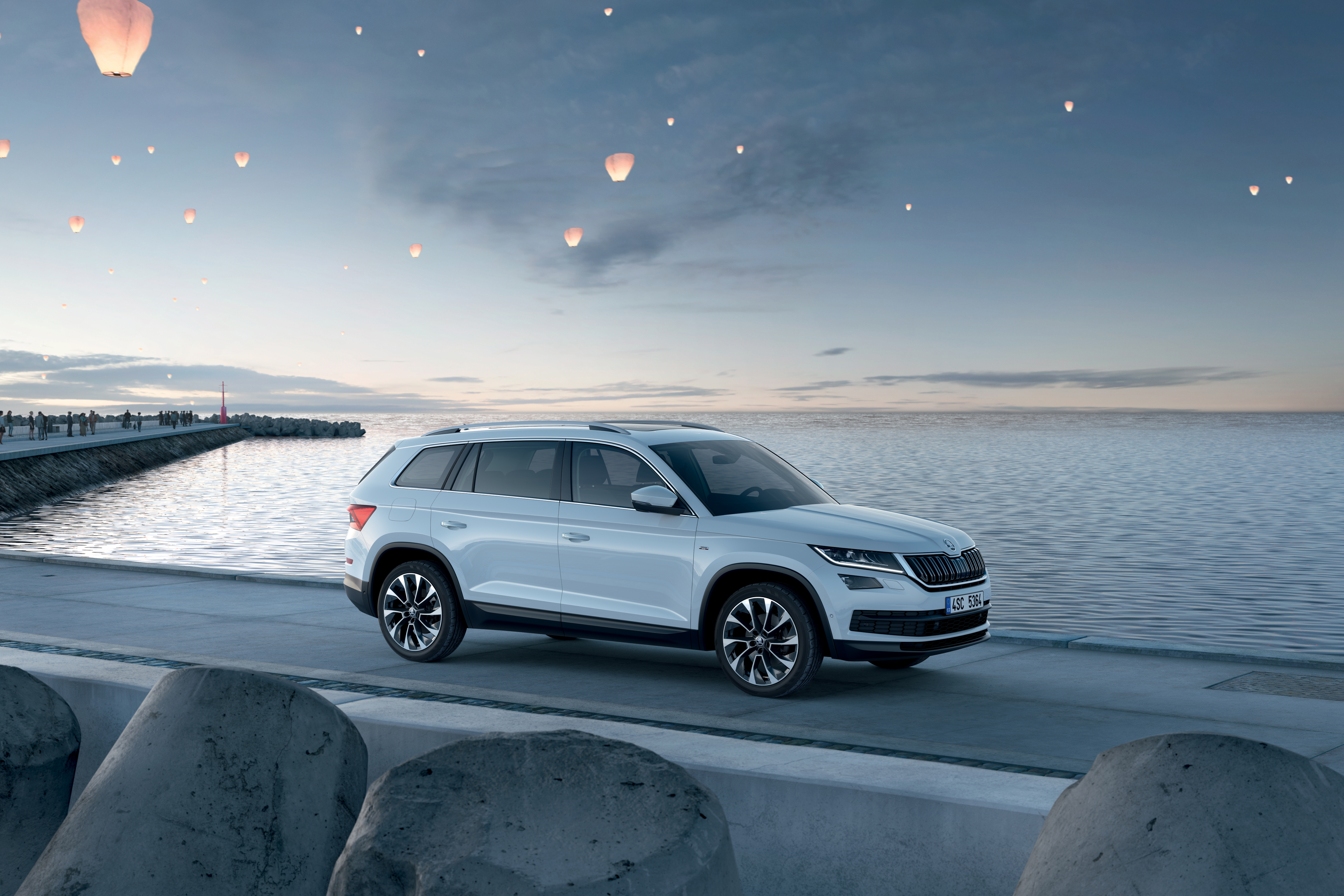 Škoda Kodiaq parkiran na pomolu. Na nebu so vidni lampijončki