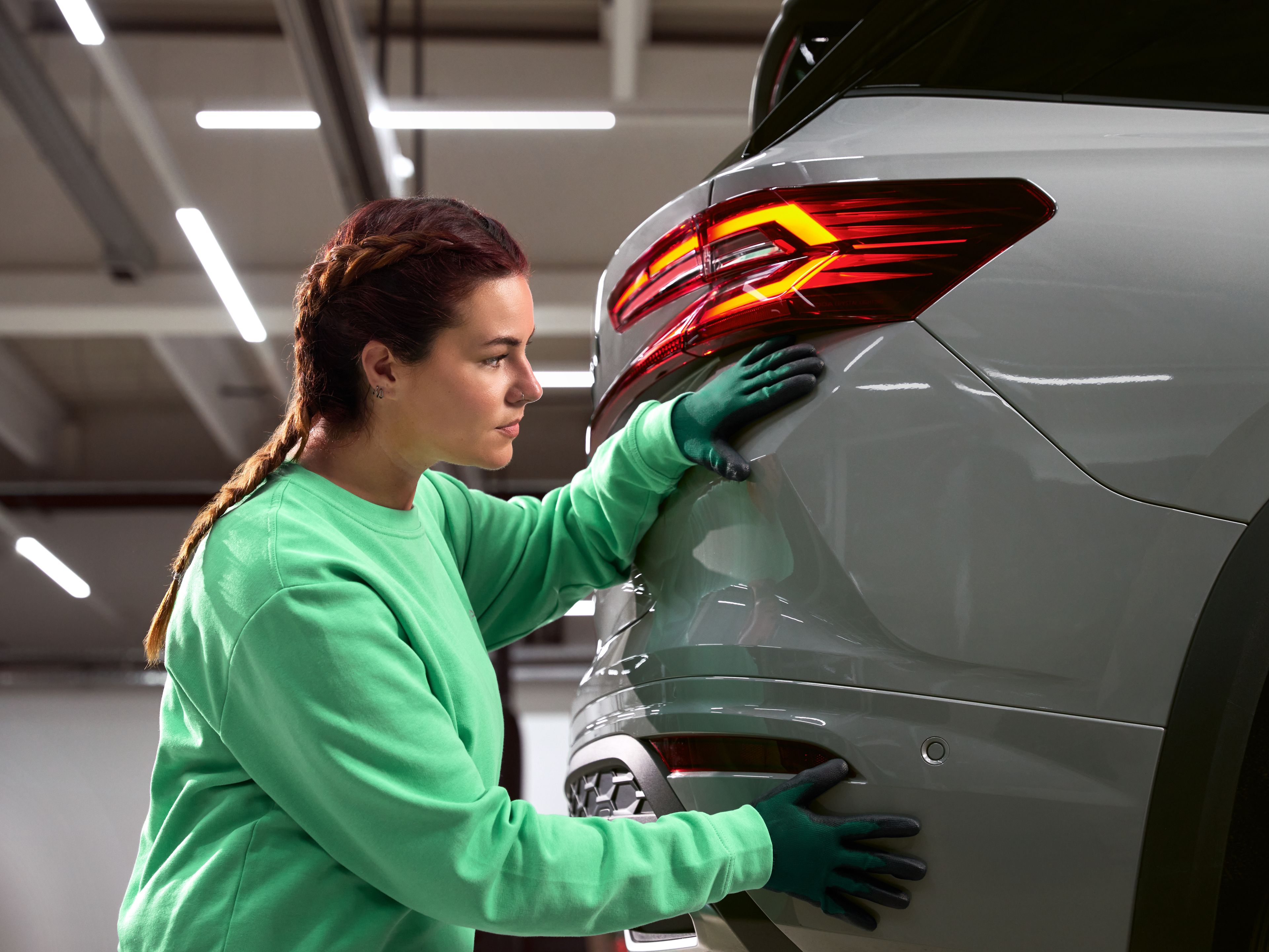 Serviserka preverja poškodbo karoserije na vozilu v servisni delavnici Škoda